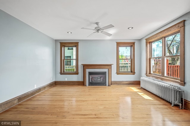 unfurnished living room with light hardwood / wood-style flooring, radiator heating unit, and ceiling fan