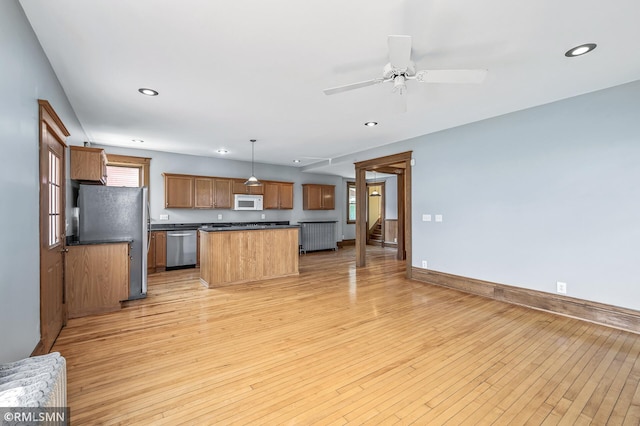 kitchen featuring appliances with stainless steel finishes, light hardwood / wood-style flooring, hanging light fixtures, a center island, and ceiling fan