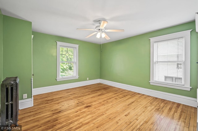 empty room with ceiling fan, light hardwood / wood-style floors, and radiator heating unit