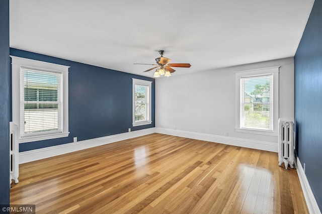 spare room featuring radiator, light hardwood / wood-style floors, and ceiling fan