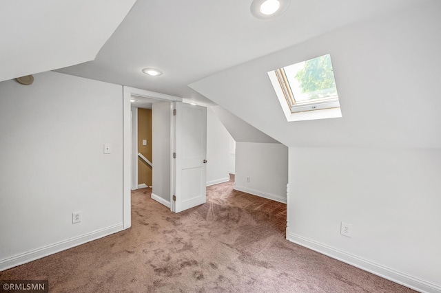 additional living space featuring light colored carpet and vaulted ceiling with skylight