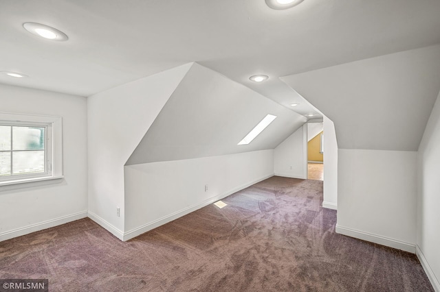 additional living space featuring carpet floors and vaulted ceiling with skylight