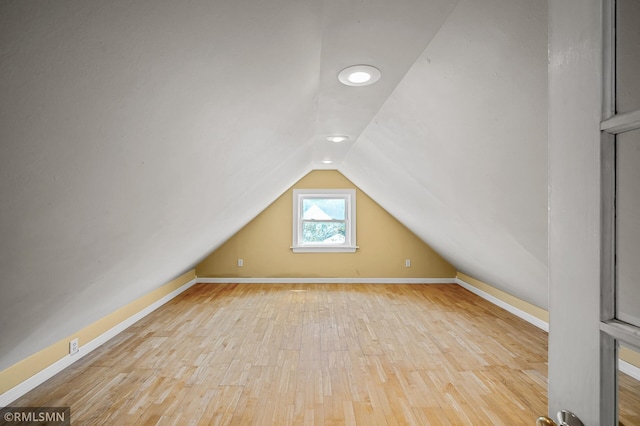 additional living space with vaulted ceiling and light hardwood / wood-style flooring