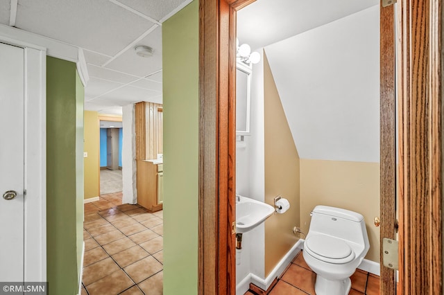 bathroom with a paneled ceiling, tile patterned flooring, and toilet