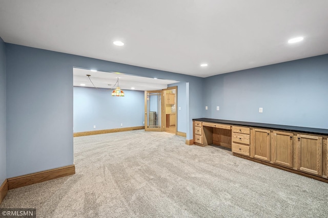 interior space featuring built in desk, light colored carpet, and decorative light fixtures