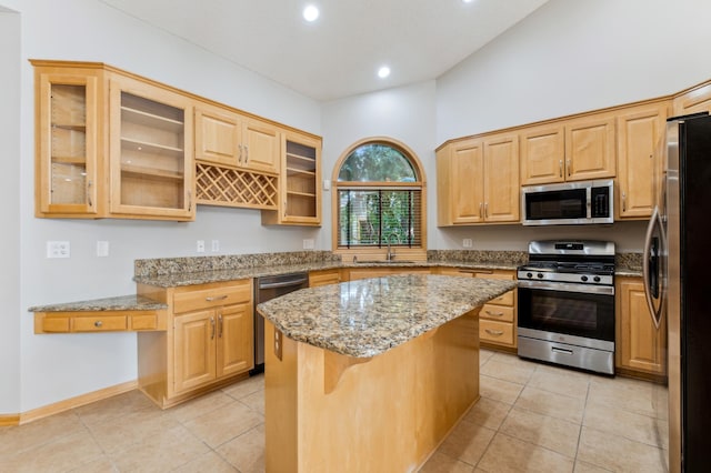 kitchen with sink, a breakfast bar area, appliances with stainless steel finishes, a center island, and light stone countertops