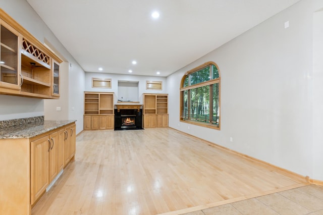 kitchen with light brown cabinetry, light hardwood / wood-style flooring, and stone counters