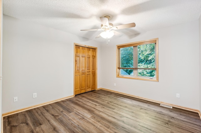 unfurnished bedroom with a closet, ceiling fan, hardwood / wood-style floors, and a textured ceiling