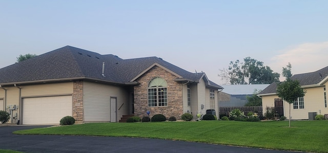 view of front of home featuring cooling unit, a garage, and a front lawn