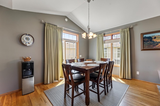 dining space with lofted ceiling, a healthy amount of sunlight, light hardwood / wood-style flooring, and a chandelier