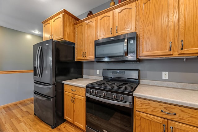 kitchen with black refrigerator with ice dispenser, gas stove, and light wood-type flooring