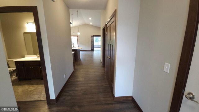 corridor with vaulted ceiling and dark hardwood / wood-style floors