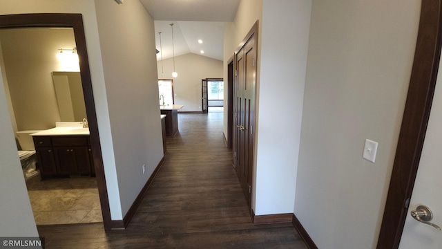 corridor featuring dark wood-type flooring, sink, and lofted ceiling