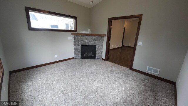 unfurnished living room with dark hardwood / wood-style flooring, a stone fireplace, and vaulted ceiling