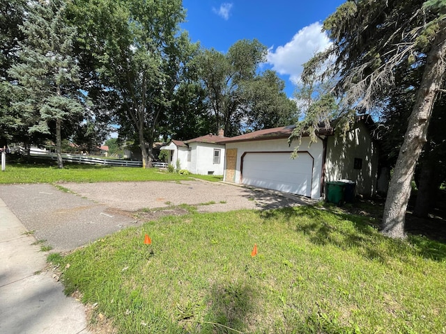 view of side of property with stucco siding, driveway, fence, a yard, and an attached garage