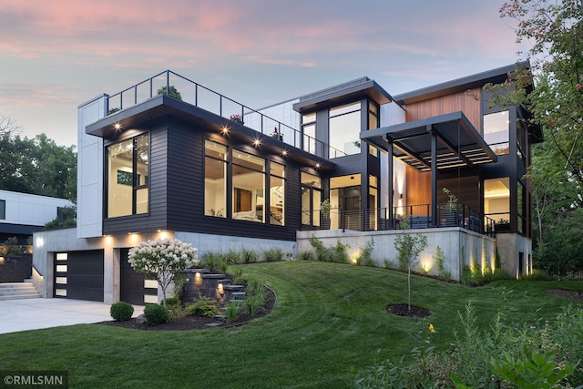 view of front of property with a balcony, a lawn, and a garage