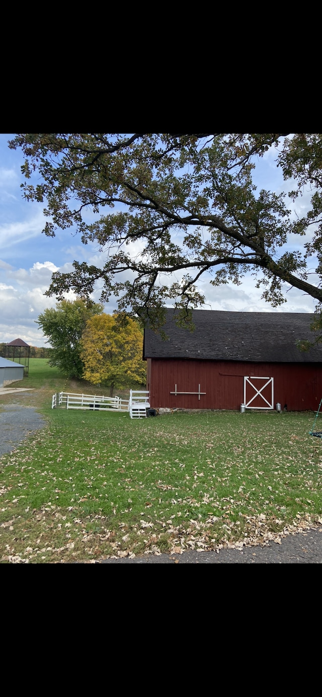 view of barn with a yard and fence