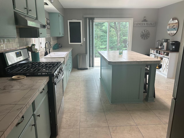 kitchen with gas stove, a sink, tile countertops, and green cabinets