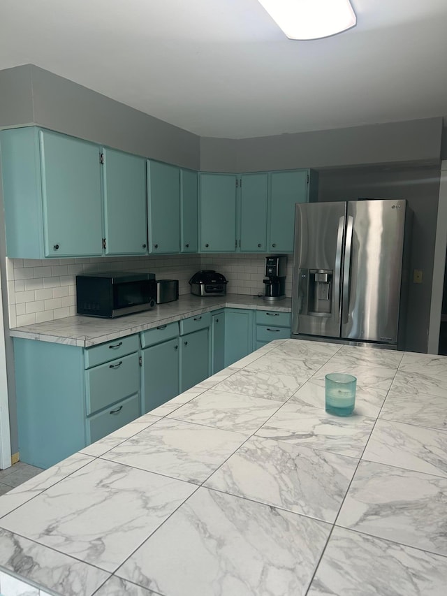 kitchen featuring green cabinets, light countertops, tasteful backsplash, and stainless steel fridge with ice dispenser