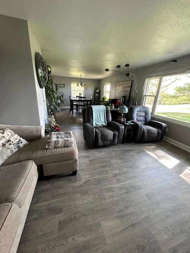 living area with a textured ceiling, dark wood-style flooring, and baseboards