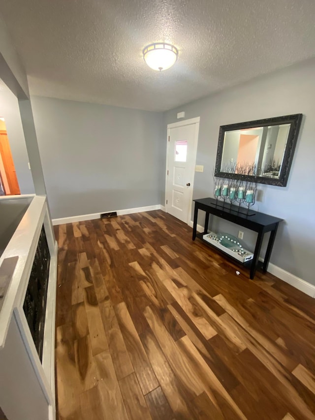 foyer entrance featuring a textured ceiling, wood finished floors, and baseboards