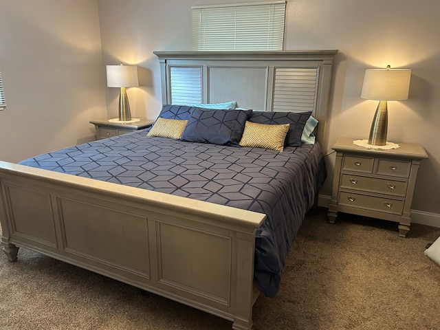 bedroom with dark carpet and baseboards