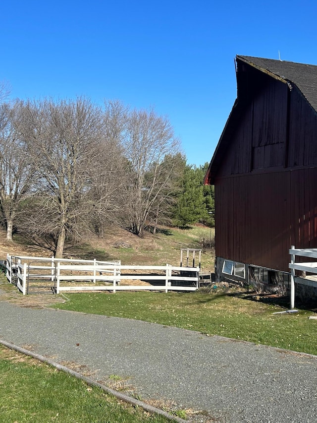 view of yard with a barn, fence, an outdoor structure, and a rural view