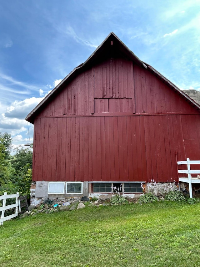 view of barn featuring fence and a yard