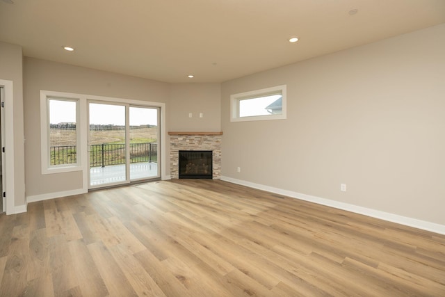 unfurnished living room featuring light hardwood / wood-style floors and a stone fireplace