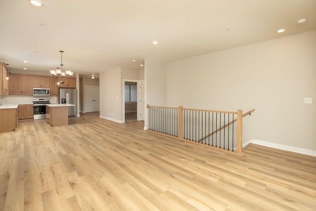 kitchen featuring a chandelier, stainless steel appliances, light hardwood / wood-style floors, decorative light fixtures, and a center island