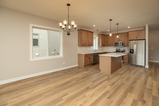 kitchen with light hardwood / wood-style flooring, stainless steel appliances, a kitchen island, and pendant lighting