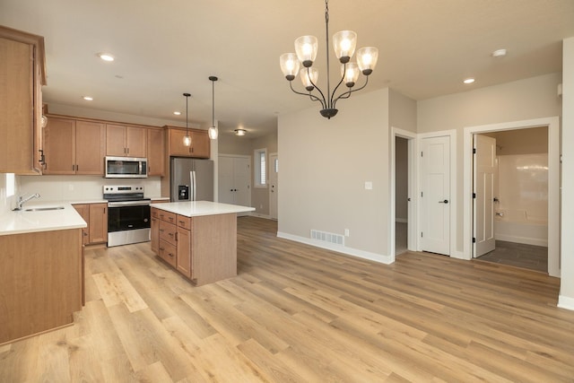 kitchen with appliances with stainless steel finishes, light hardwood / wood-style flooring, decorative light fixtures, and a kitchen island