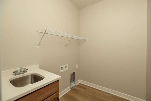 clothes washing area with hardwood / wood-style floors, sink, washer hookup, and cabinets