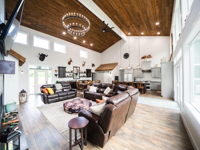 living room featuring high vaulted ceiling, light wood-type flooring, ceiling fan with notable chandelier, and wood ceiling