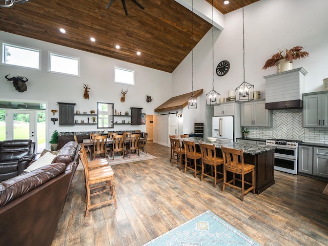 kitchen with high vaulted ceiling, white refrigerator with ice dispenser, dark hardwood / wood-style floors, and dark stone counters