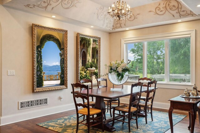 dining area with a wealth of natural light, dark hardwood / wood-style flooring, a mountain view, and an inviting chandelier