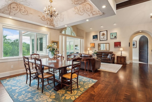 dining room featuring plenty of natural light, dark wood-type flooring, a chandelier, and a towering ceiling