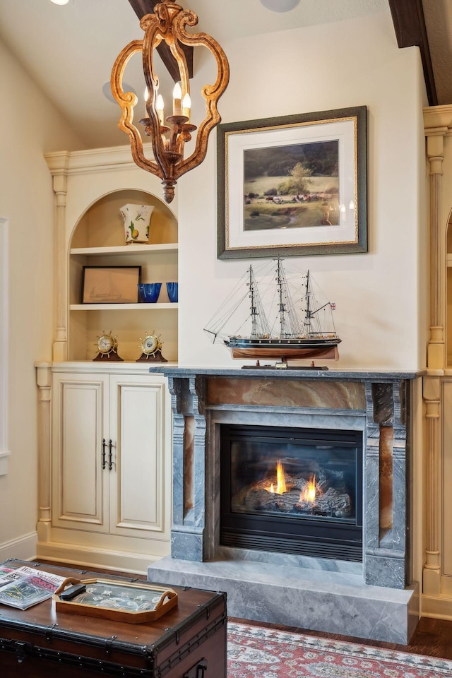 interior space with a fireplace, built in shelves, wood-type flooring, and a notable chandelier