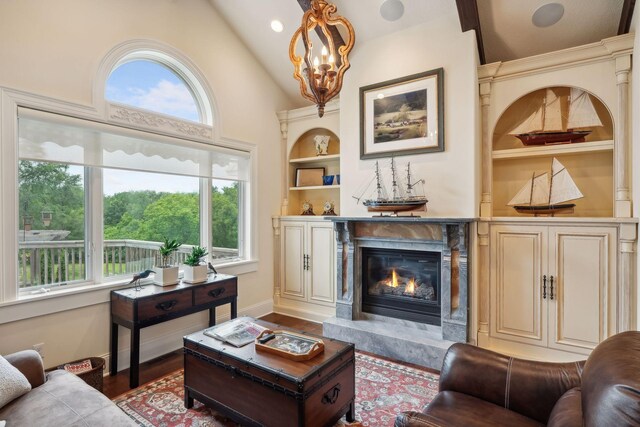 living room with built in shelves, wood-type flooring, lofted ceiling, and a high end fireplace