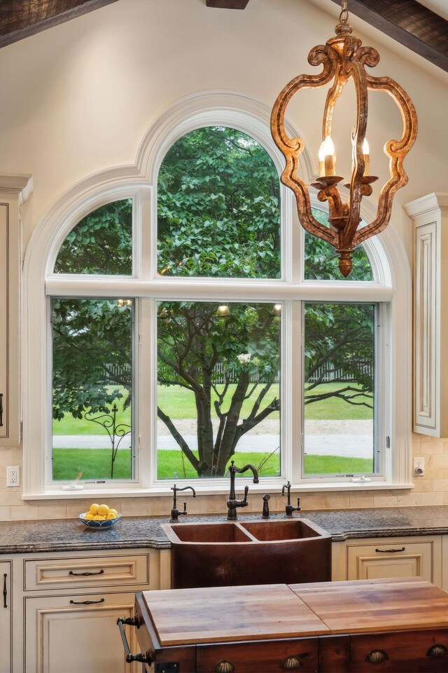 kitchen with vaulted ceiling with beams, plenty of natural light, sink, and tasteful backsplash