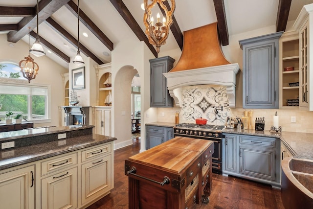 kitchen with hanging light fixtures, range with gas stovetop, lofted ceiling with beams, wood counters, and custom exhaust hood