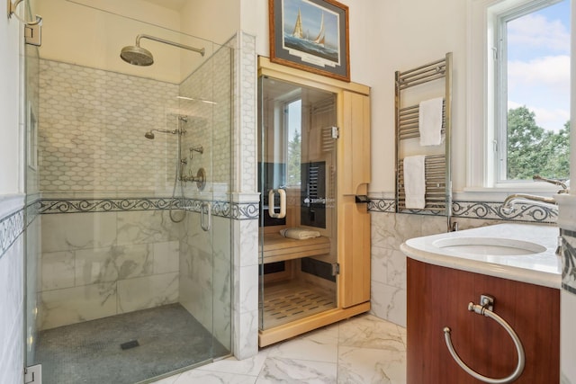 bathroom with tile walls, vanity, a shower with door, and radiator