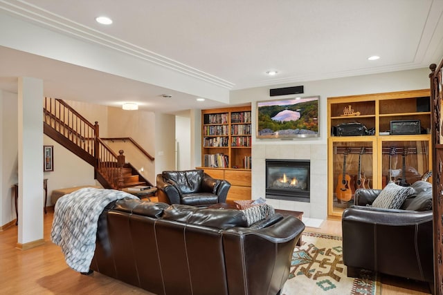 living room with a fireplace, light hardwood / wood-style flooring, built in features, and crown molding