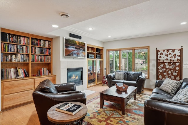 living room featuring built in features, a tile fireplace, and hardwood / wood-style floors