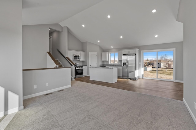 unfurnished living room featuring light carpet and high vaulted ceiling