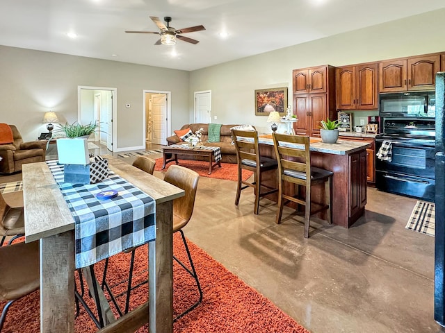 kitchen featuring a breakfast bar area, concrete flooring, black appliances, a center island, and ceiling fan