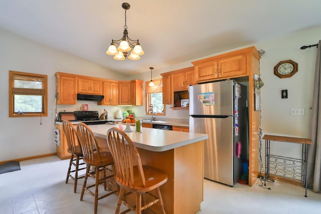 kitchen featuring a kitchen bar, appliances with stainless steel finishes, an inviting chandelier, a center island, and lofted ceiling