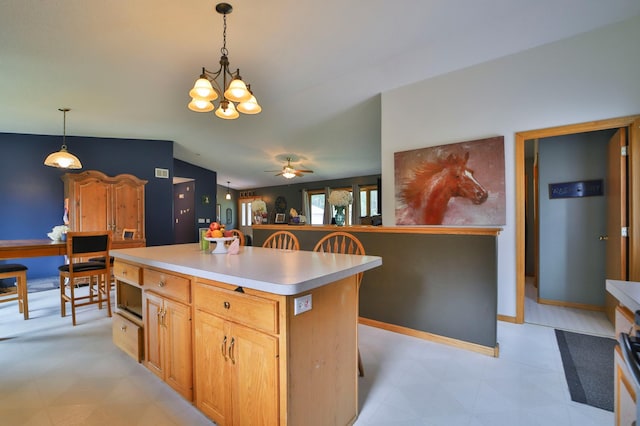 kitchen featuring ceiling fan with notable chandelier, a center island, hanging light fixtures, and lofted ceiling