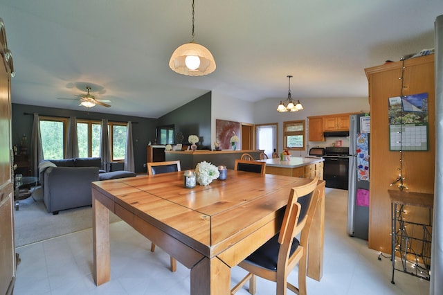 dining area with ceiling fan with notable chandelier, a healthy amount of sunlight, and vaulted ceiling