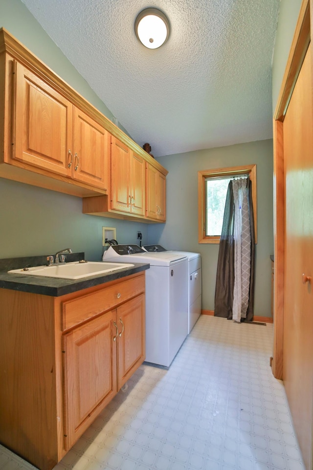 clothes washing area with separate washer and dryer, sink, cabinets, and a textured ceiling